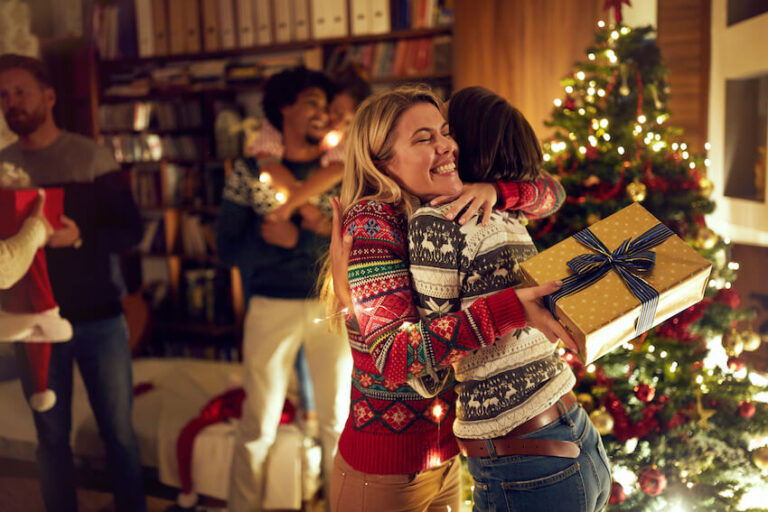 Friends exchanging gifts and laughing together during a Secret Santa gathering.